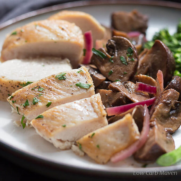 Roasted balsamic marinated mushrooms and purple onions on a plate between sliced baked chicken breast sprinkled with pepper and chopped parsley on the left and steamed broccoli rabe to the right.