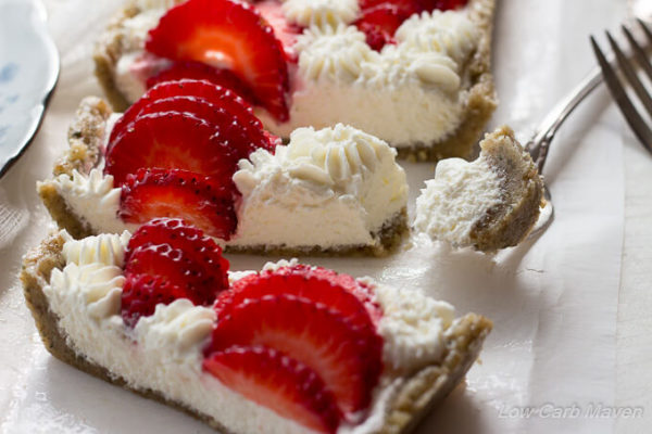 Close-up overhead view of a slice low carb strawberry cream cheese tart in a hemp walnut crust decorated with sliced strawberries and piped cream cheese stars.