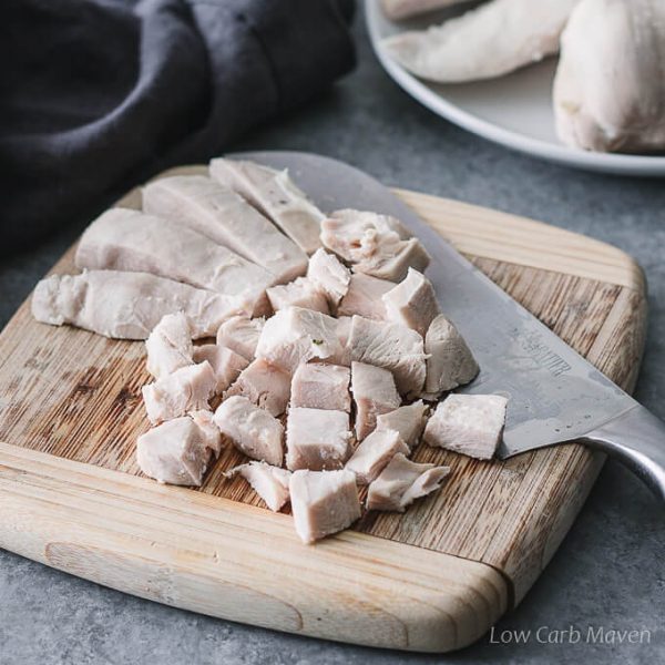 Cubed poached chicken on a cutting board. 
