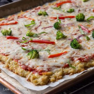 Chicken crust pizza with cheese and vegetables in a sheet pan.