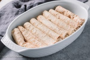 Rolled chicken enchiladas in white baking dish.