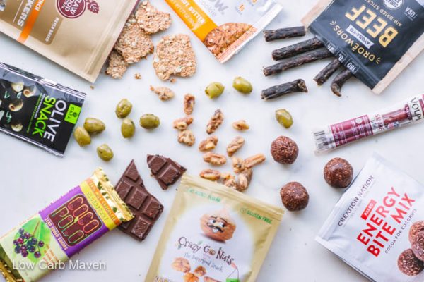 Keto Krate subscription box products: Cookie, beef jerky, meat stick, protein bites, walnuts, chocolate bar, olives, flax crackers. 