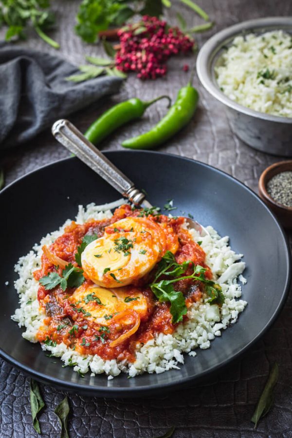 Keto egg masala or egg curry with cauliflower rice in a bowl with spoon.