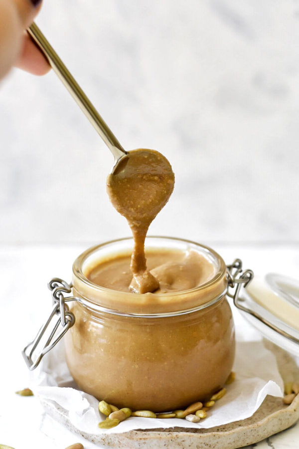 Homemade sunflower seed butter running off a spoon into a jar