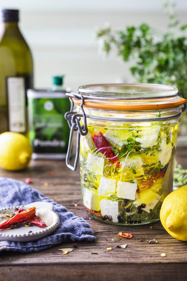 Marinated feta cheese with herbs, lemon zest, red pepper and olive oil in a jar