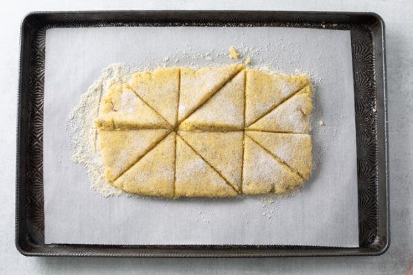 Lemon Poppy Seed Scones cut into triangles on a sheet pan.