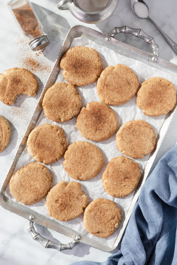 Keto snickerdoodle cookies with cinnamon on a parchment lined tray with blue napkin
